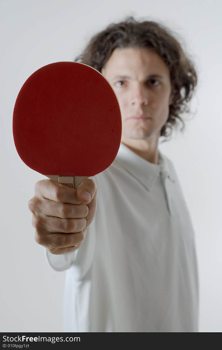 Man holding a ping-pong paddle stares ahead with a serious look on his face. Vertically framed photograph. Man holding a ping-pong paddle stares ahead with a serious look on his face. Vertically framed photograph.