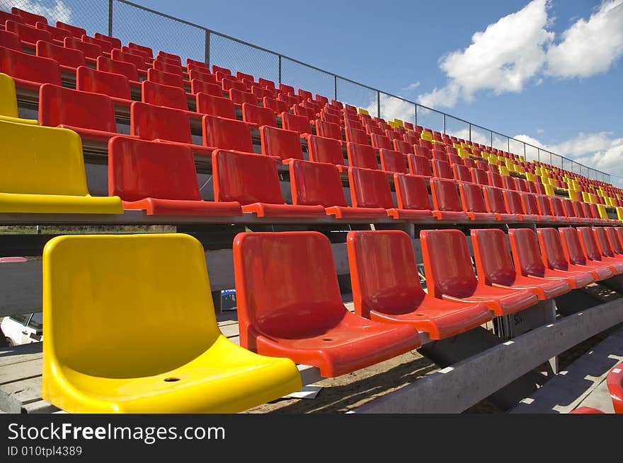 Red and yellow seats on a background of the sky with clouds. Red and yellow seats on a background of the sky with clouds.