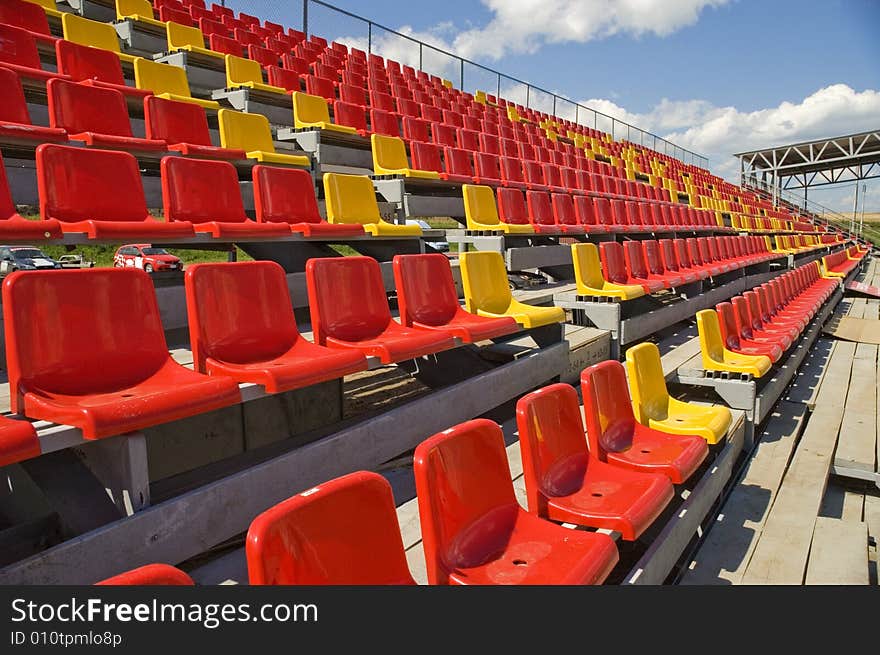 Red and yellow seats on a background of the sky with clouds. Red and yellow seats on a background of the sky with clouds.