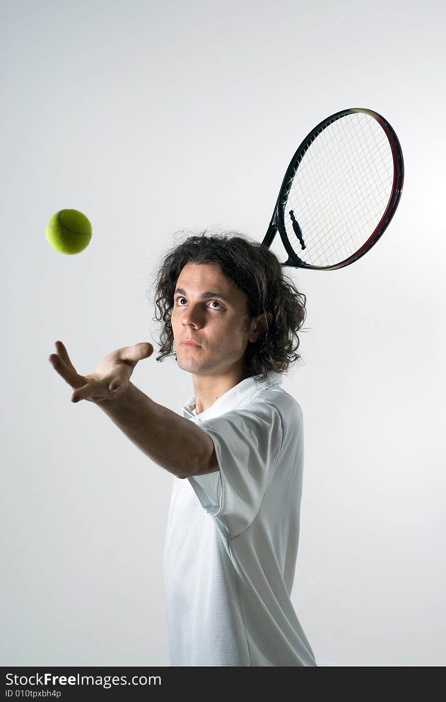 An action shot of a tennis player serving a tennis ball. The ball is in the air, and the model is staring at it. Vertically framed shot. An action shot of a tennis player serving a tennis ball. The ball is in the air, and the model is staring at it. Vertically framed shot.