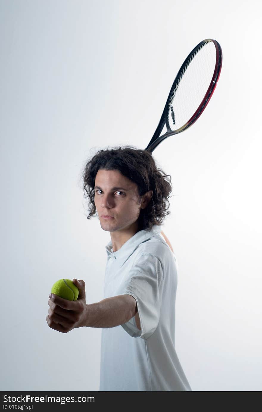 Man holds a tennis ball in one hand and a tennis racket in the other. He has a serious look on his face. Vertically framed photograph. Man holds a tennis ball in one hand and a tennis racket in the other. He has a serious look on his face. Vertically framed photograph