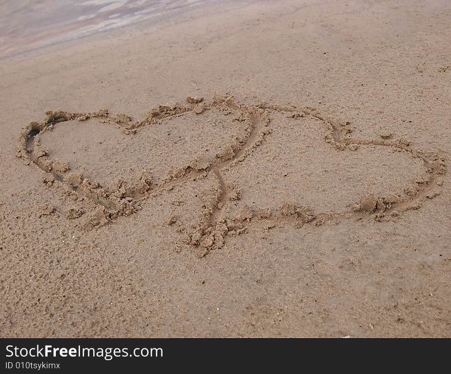 Figure of two hearts on sand of a beach