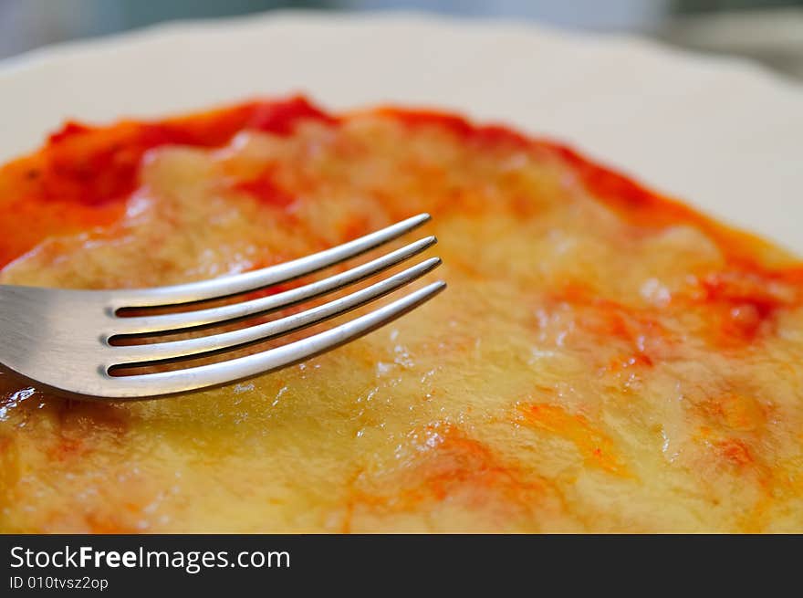 Close shot about a little tomato and mozzarella cheese pizza, with a fork. Close shot about a little tomato and mozzarella cheese pizza, with a fork.