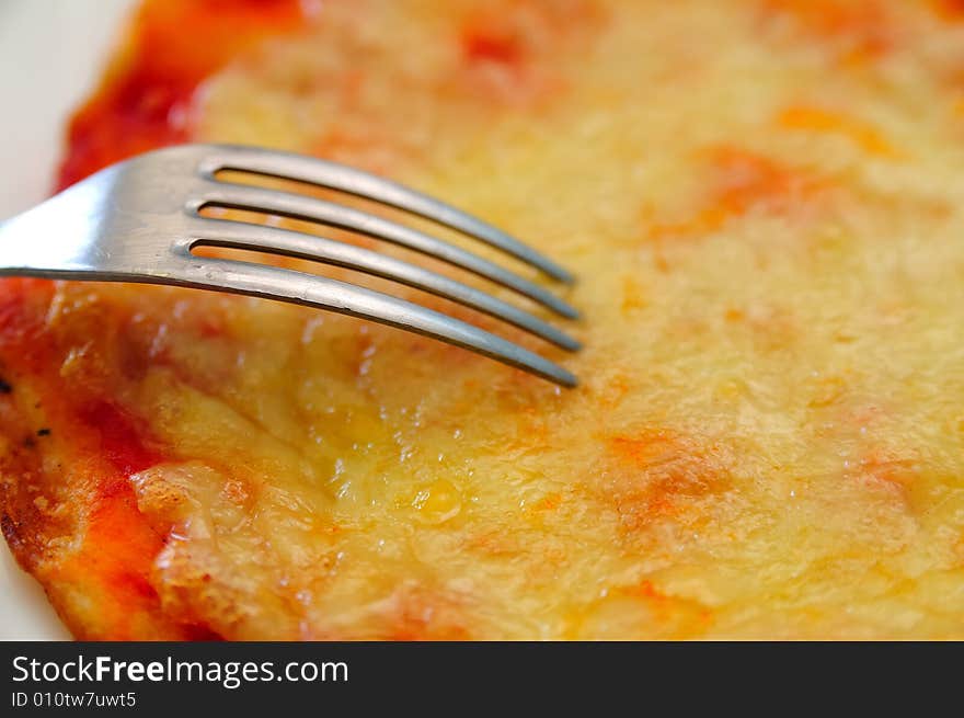 Close shot about a little tomato and mozzarella cheese pizza, with a fork. Close shot about a little tomato and mozzarella cheese pizza, with a fork.