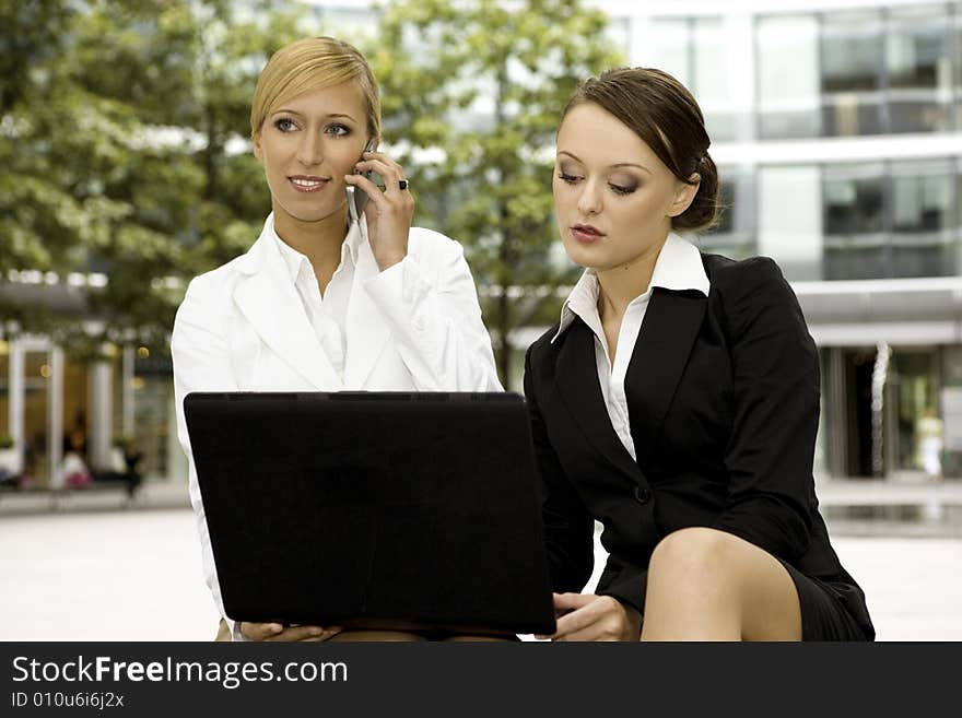 Two attractive businesswomen working on laptop outdoors. Two attractive businesswomen working on laptop outdoors