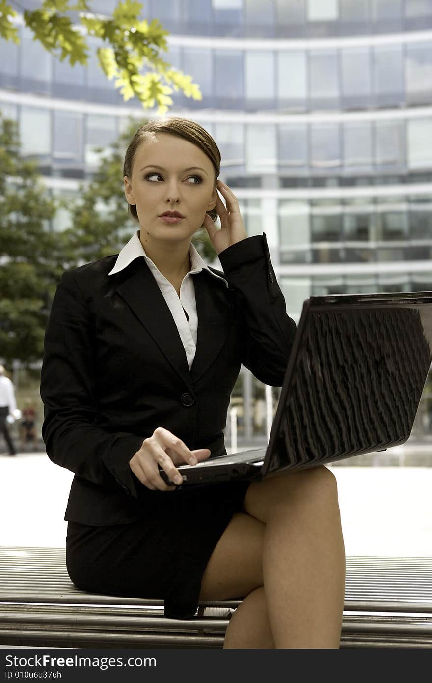 Young and attractive brunette businesswoman working on laptop outdoors. Young and attractive brunette businesswoman working on laptop outdoors