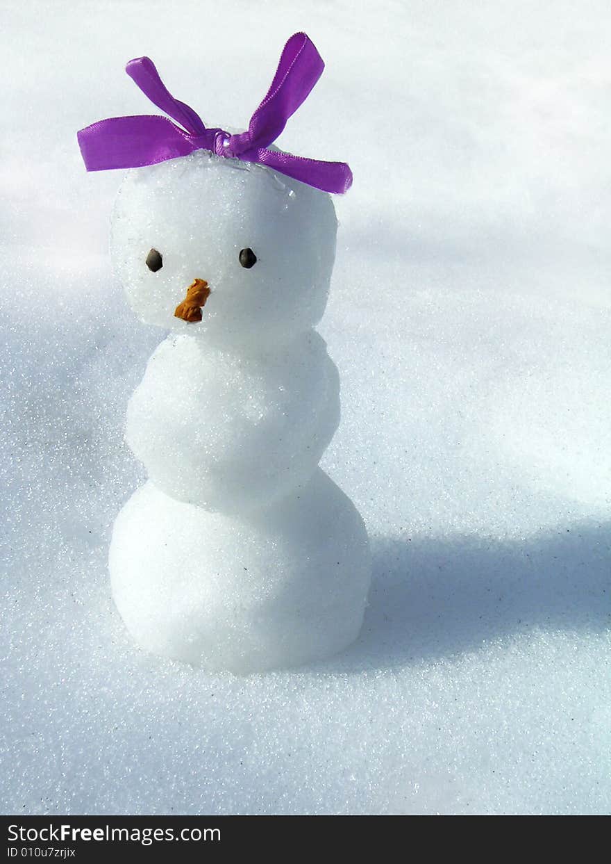 Snowgirl with a bow on a background of a snow. Snowgirl with a bow on a background of a snow