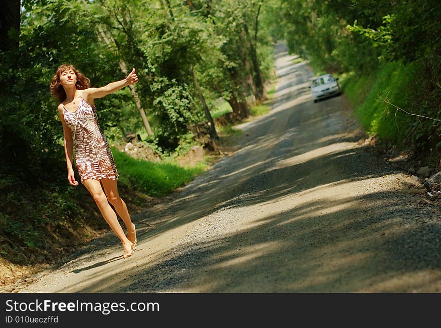 Pretty girl hitching hiking on country road. Pretty girl hitching hiking on country road.