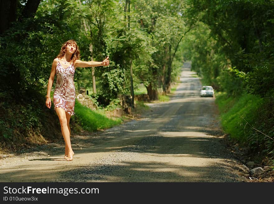 Pretty girl hitching hiking on country road. Pretty girl hitching hiking on country road.