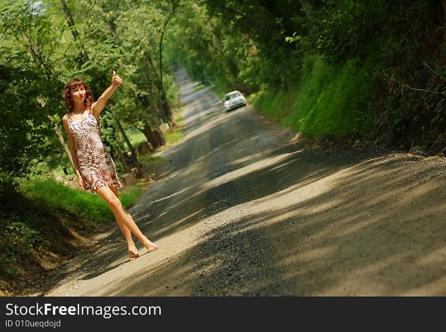 Pretty girl hitching hiking on country road. Pretty girl hitching hiking on country road.