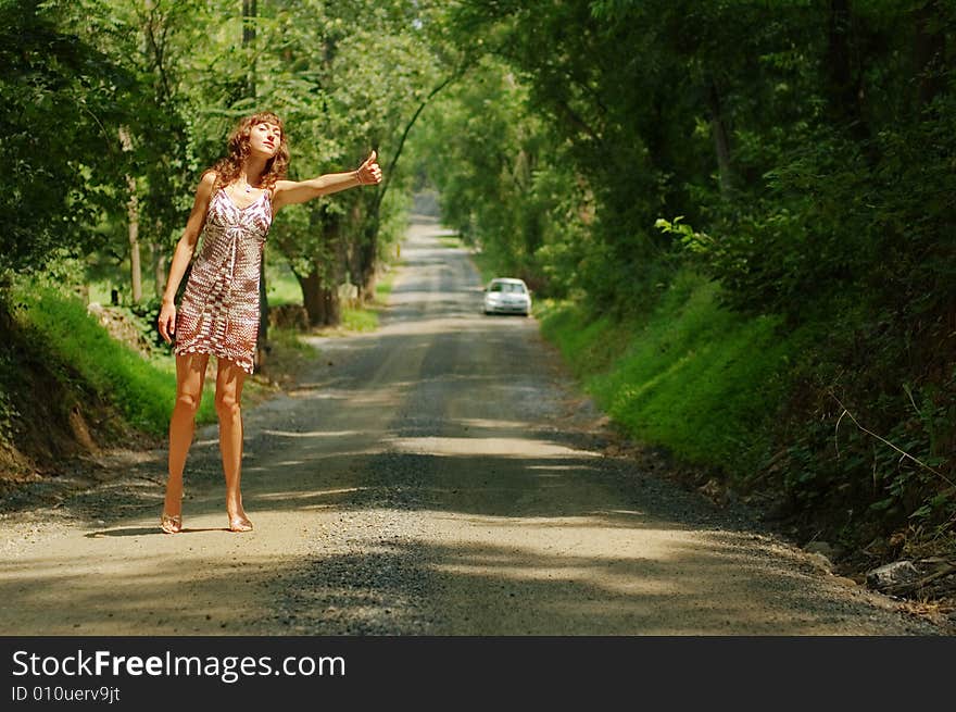 Pretty girl hitching hiking on country road. Pretty girl hitching hiking on country road.