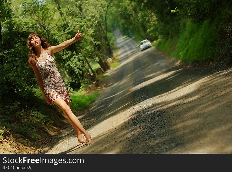 Pretty girl hitching hiking on country road. Pretty girl hitching hiking on country road.