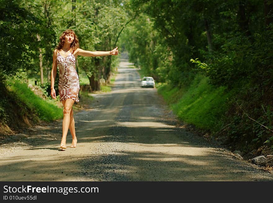 Pretty girl hitching hiking on country road. Pretty girl hitching hiking on country road.