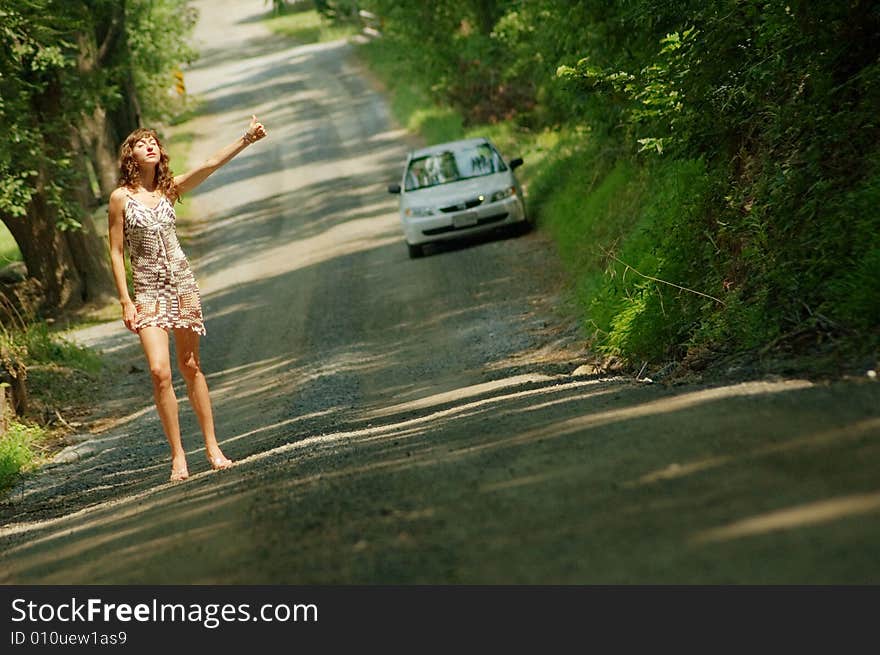 Pretty girl hitching hiking on country road. Pretty girl hitching hiking on country road.