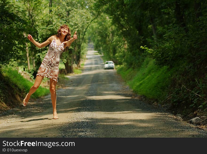 Pretty girl hitching hiking on country road. Pretty girl hitching hiking on country road.