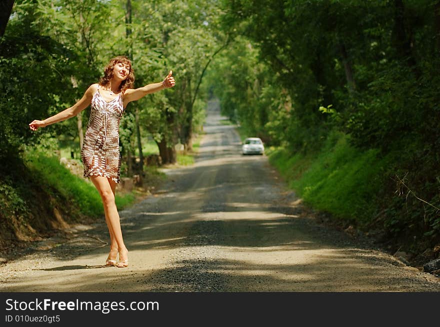 Pretty girl hitching hiking on country road. Pretty girl hitching hiking on country road.