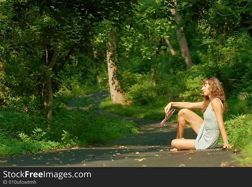 Pretty girl sitting on forest path.