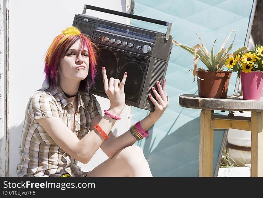 Punk girl with brightly colored hair sitting on trailer step holding boom box. Punk girl with brightly colored hair sitting on trailer step holding boom box