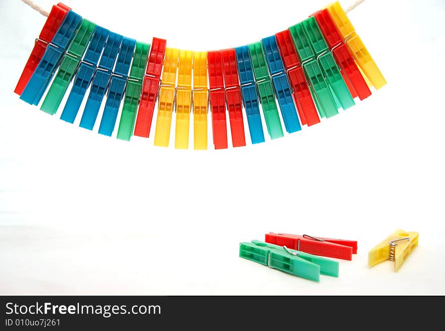 Set of the varicoloured clothes-pegs on rope and several clothes-pegs under him on white background. Set of the varicoloured clothes-pegs on rope and several clothes-pegs under him on white background