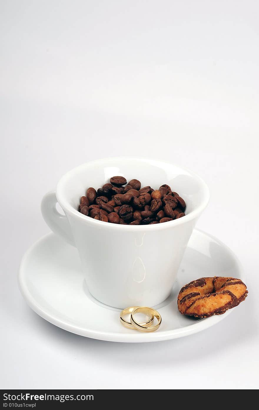 Macro studio shot of a cup of coffee beans and wedding rings