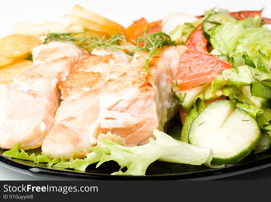 Stake from a salmon with vegetables on a plate. Closeup.