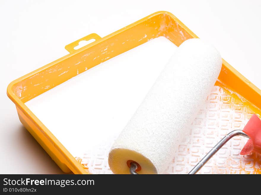 Paint-roller and tray with paint on a white background. Paint-roller and tray with paint on a white background