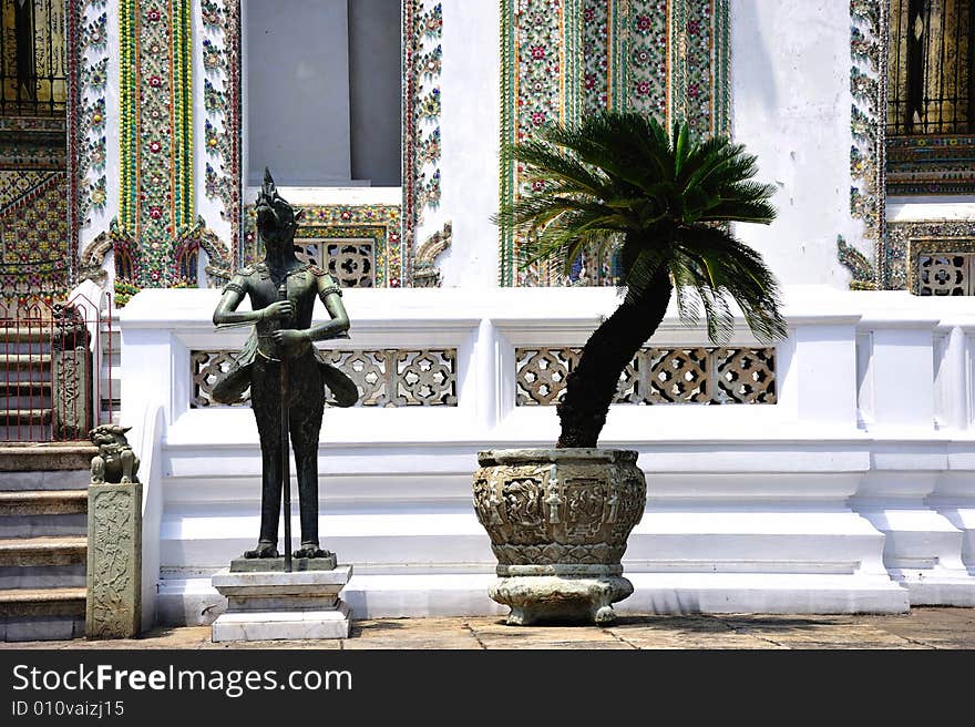 Thailand Bangkok; the wat Phra Kaew shelter the most sacred image of Thailand the Emerald Buddha. View of the courtyard with a palme tree and a mythological being; a kinnari. Thailand Bangkok; the wat Phra Kaew shelter the most sacred image of Thailand the Emerald Buddha. View of the courtyard with a palme tree and a mythological being; a kinnari