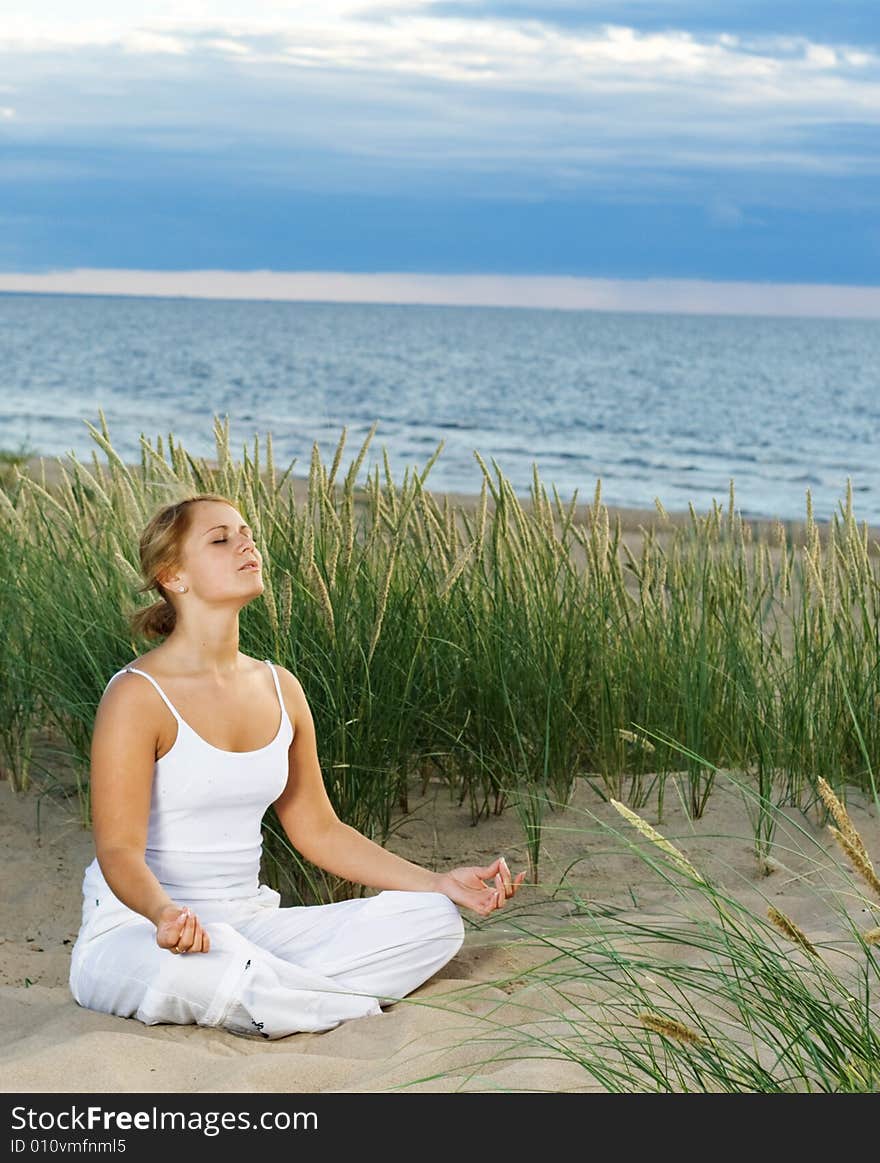 Young cute girl meditating on the beach. Young cute girl meditating on the beach.