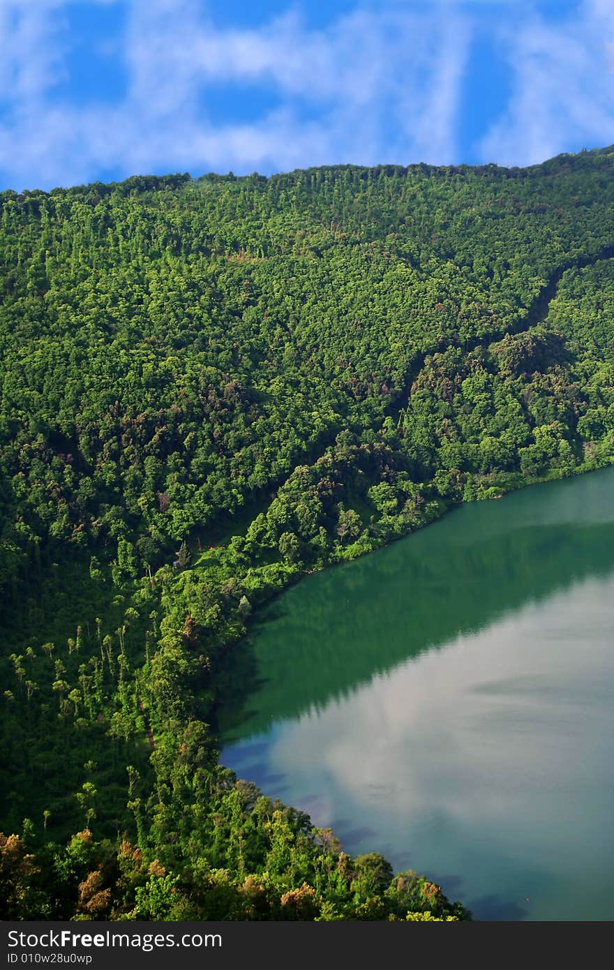 Green mountains with volcanic lake against sunny sky. Green mountains with volcanic lake against sunny sky