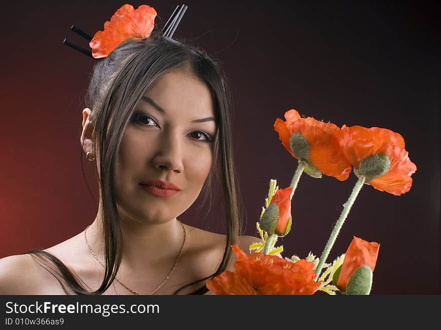 Beautiful young asiatic girl with red poppies against red