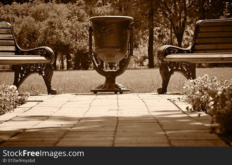 Big metal urn in the park. Sepia.