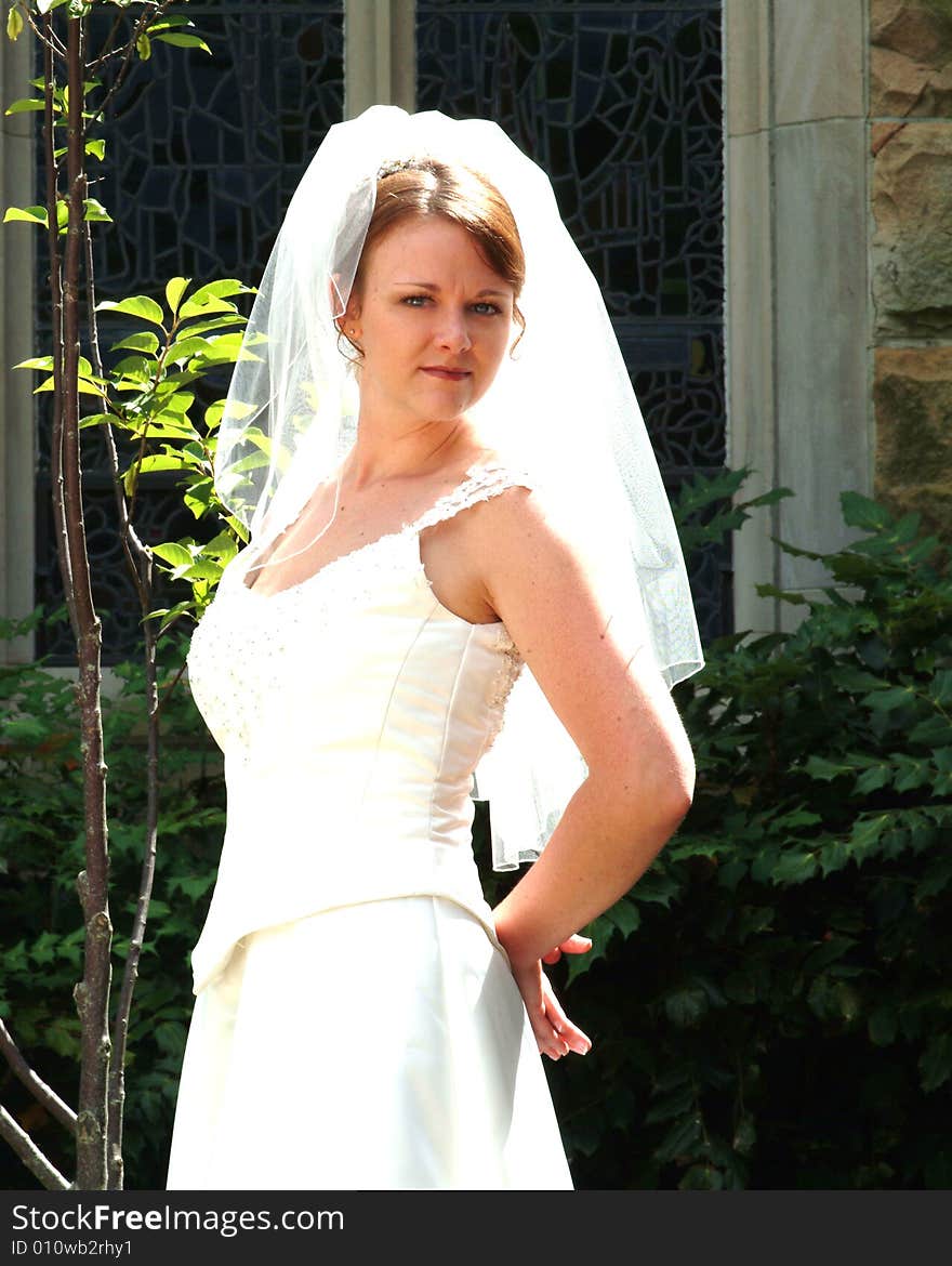 View of bride outside near stained glass window. View of bride outside near stained glass window