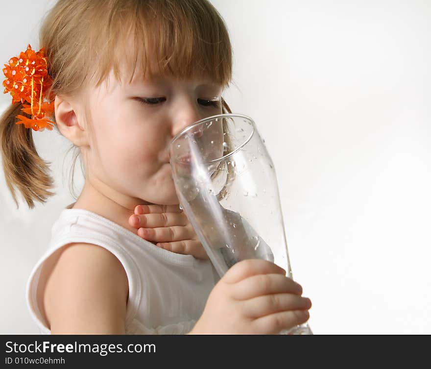 The small girl is drincking water from glas. The small girl is drincking water from glas.