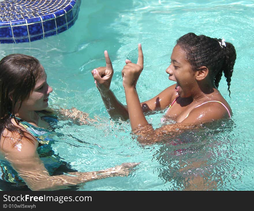 A picture of two girls talking and playing in a swimming pool. A picture of two girls talking and playing in a swimming pool.