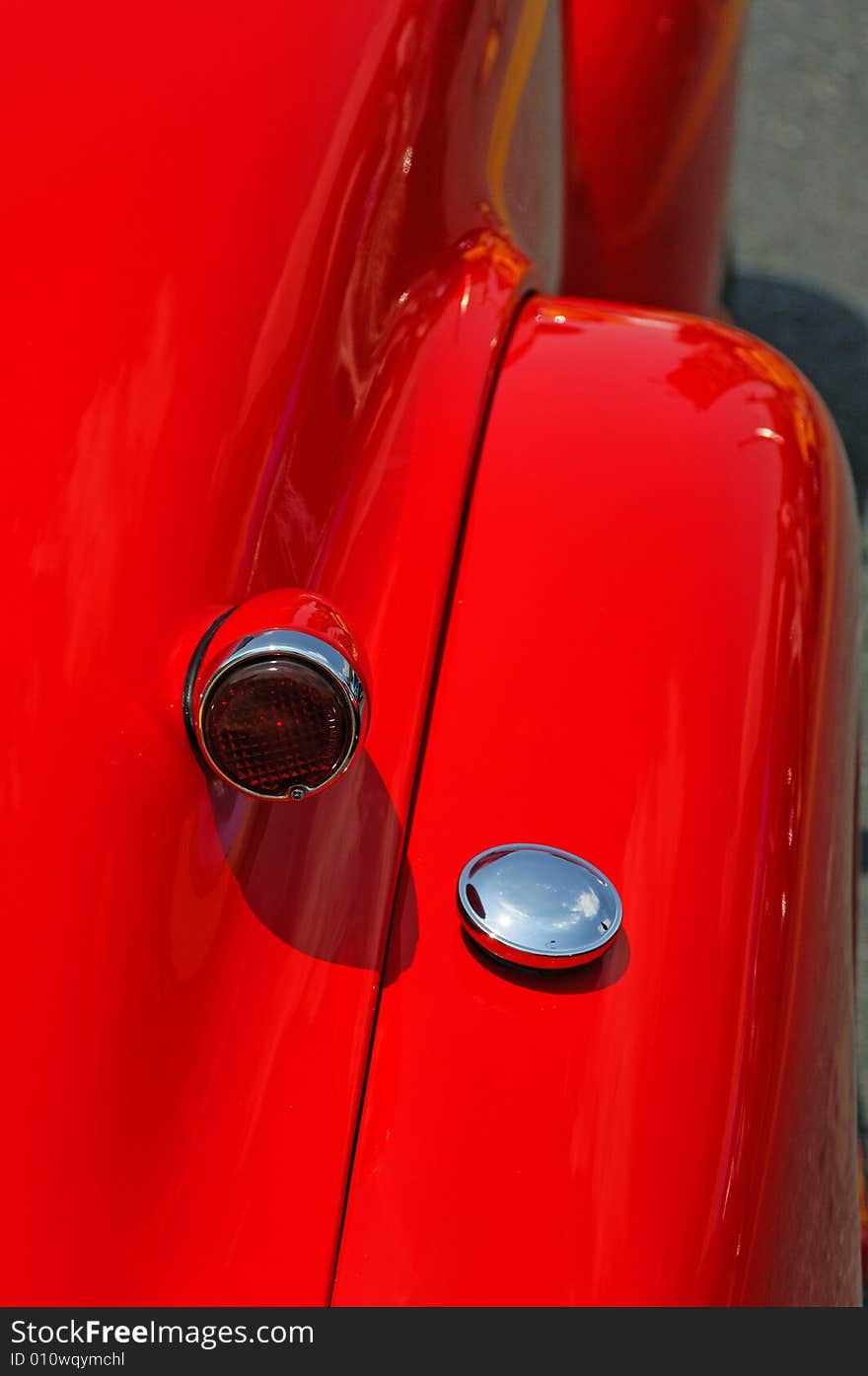 Brake light, gas cap and fender of a red antique automobile. Brake light, gas cap and fender of a red antique automobile.