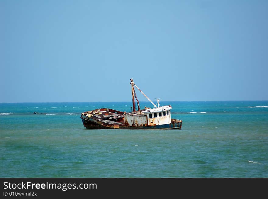 Shipwrecked fishing boat in tropical blue water