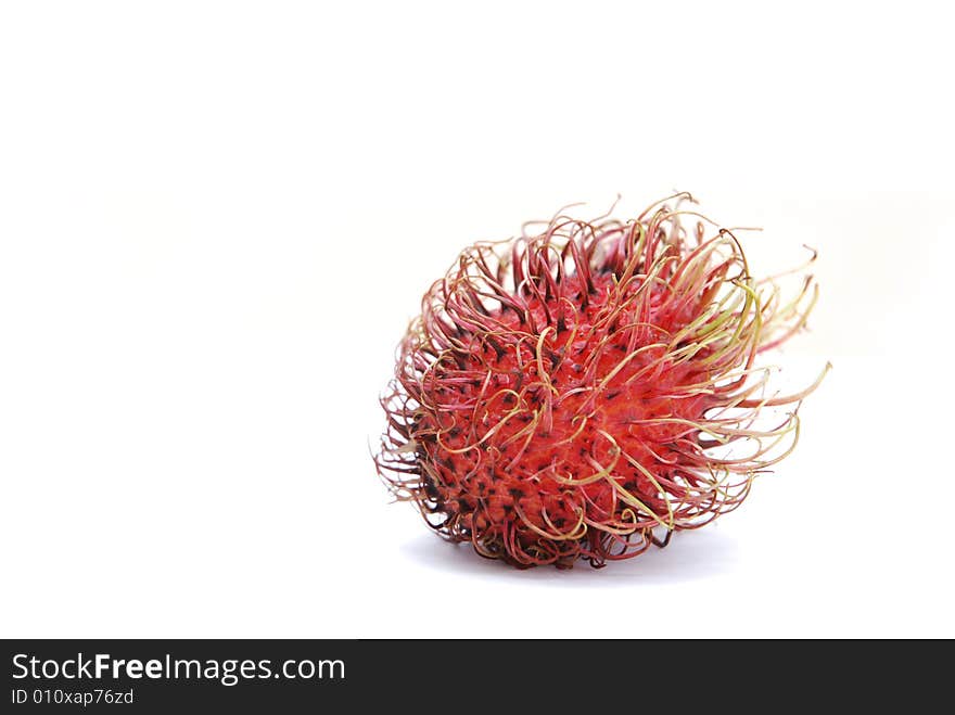 Red, spiky, whole rambutan fruit (Nephelium lappaceum), isolated on white background.