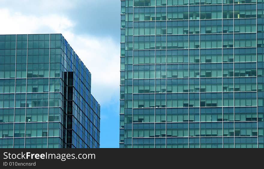 Two buildings with blue green tinted glass against a blue sky. Two buildings with blue green tinted glass against a blue sky.