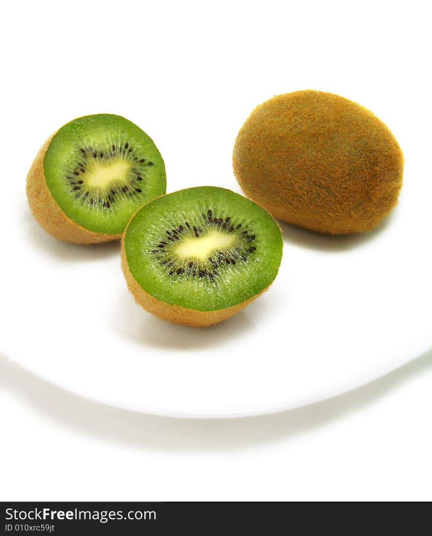 A group of cut and whole kiwis on white plate and isolated on white background. A group of cut and whole kiwis on white plate and isolated on white background