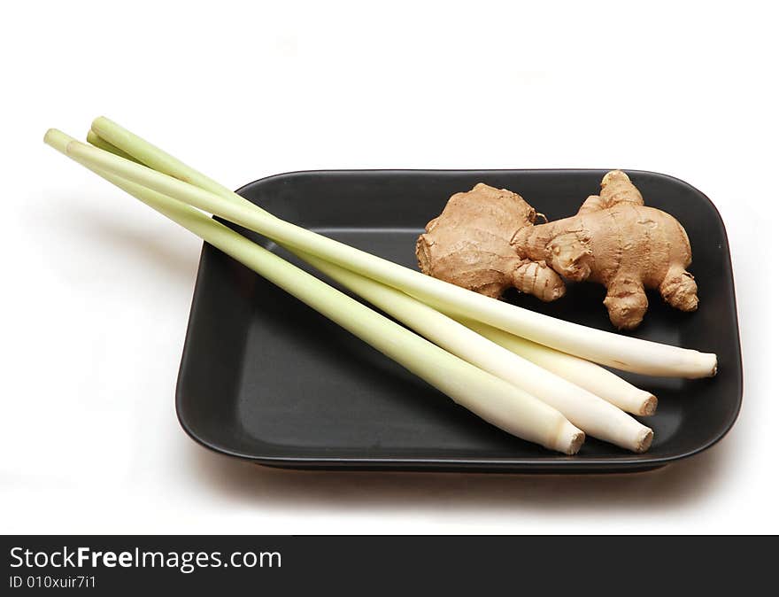 Lemon grass stalks with ginger root on black plate, isolated on white background. Lemon grass stalks with ginger root on black plate, isolated on white background.