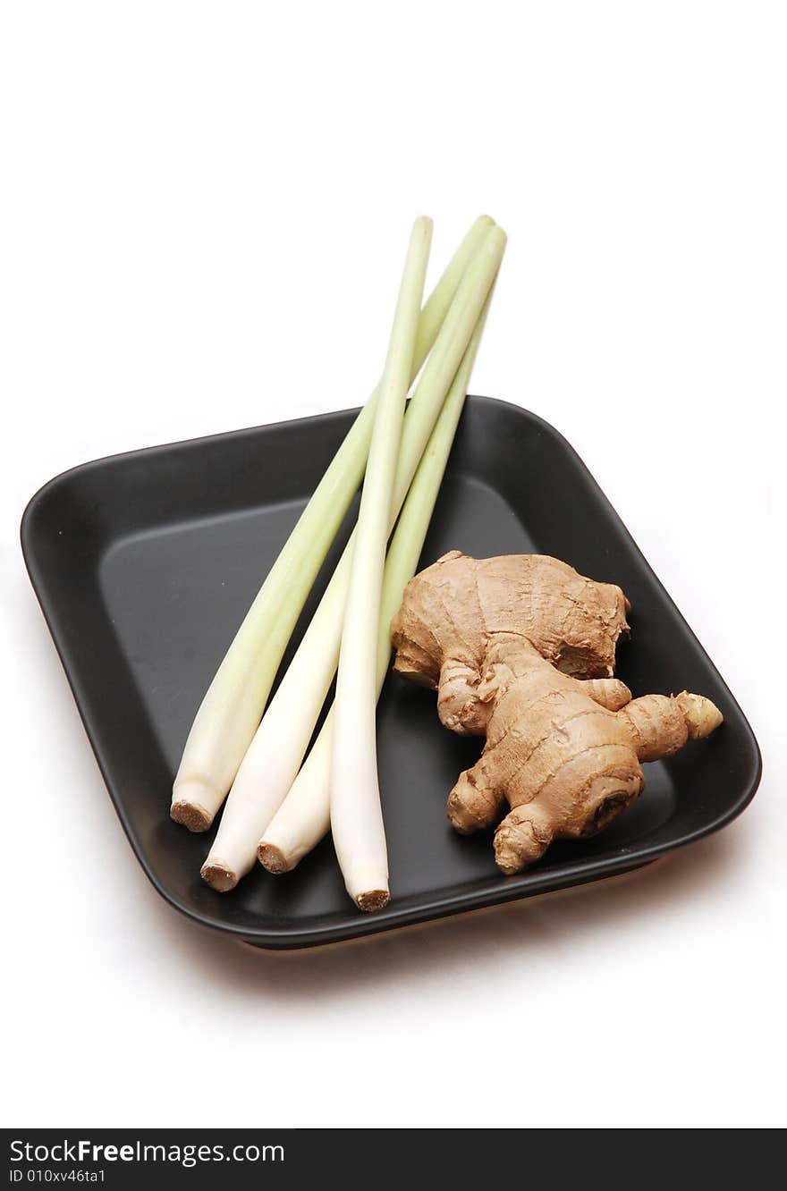 Lemon grass stalks with ginger root on black plate, isolated on white background. Lemon grass stalks with ginger root on black plate, isolated on white background.