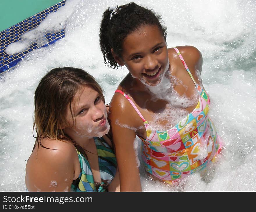 A picture of two tween girls in a jacuzzi with bubbles on them and around them. A picture of two tween girls in a jacuzzi with bubbles on them and around them.