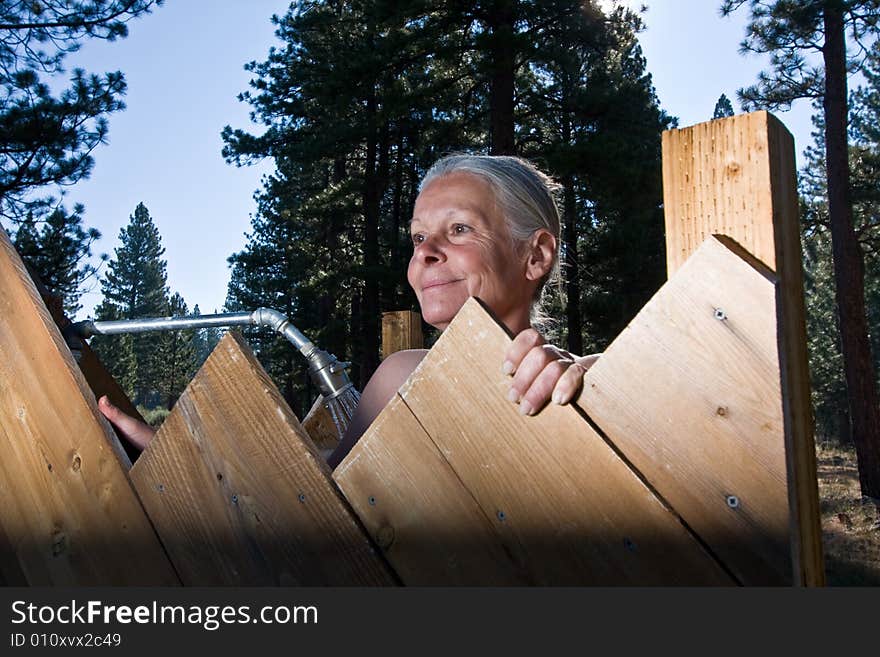 Senior woman showering outdoors in forest. Senior woman showering outdoors in forest