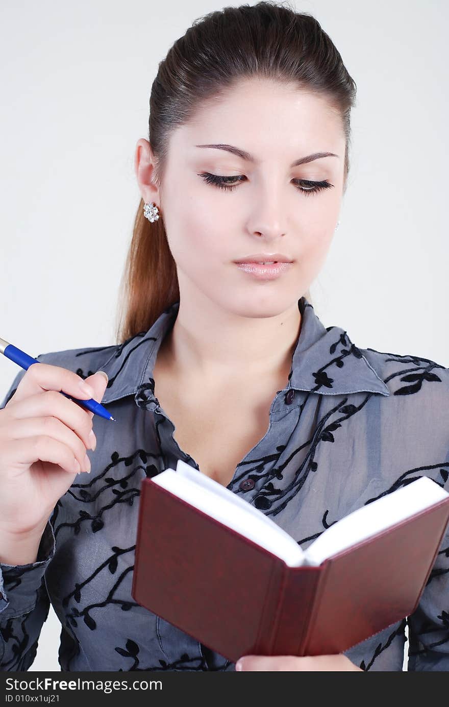 Beautiful young girl in a grey business suit with a diary and writing pen in hands. Beautiful young girl in a grey business suit with a diary and writing pen in hands