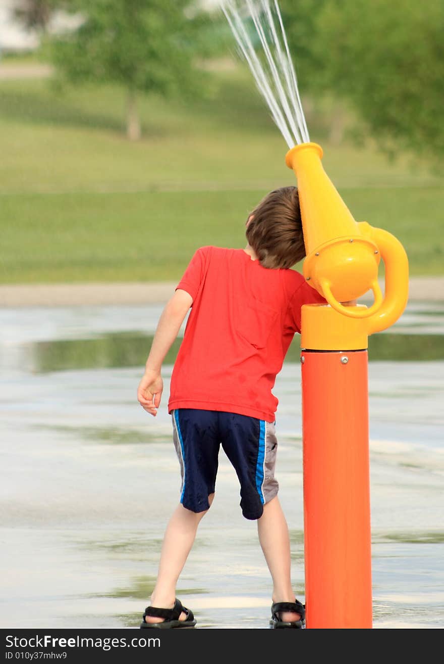 Portrait of a young boy playing with a water canon at an outdoor Spray Park