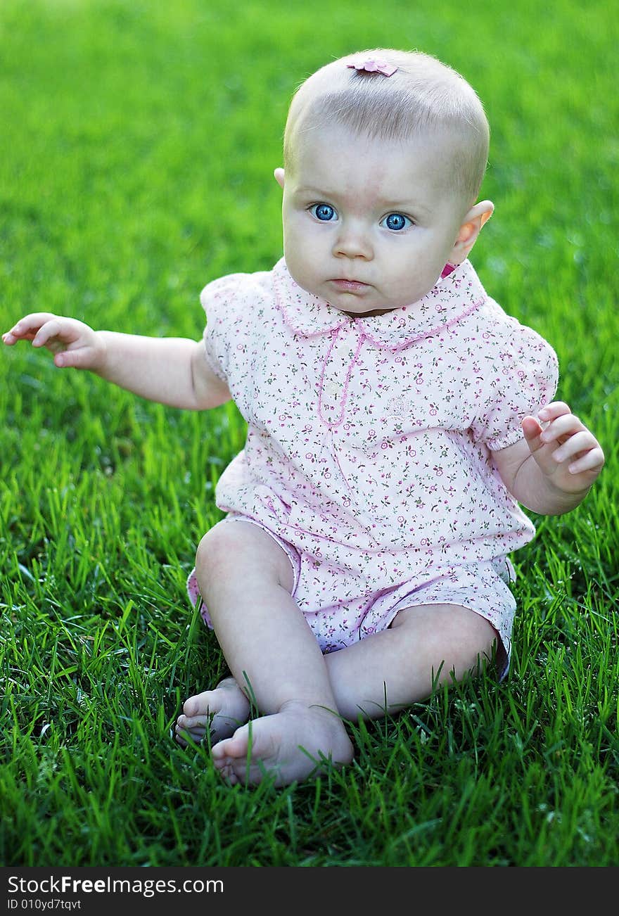 A young baby, crosses her legs while sitting, and has a confused look on her face. Vertically framed shot. A young baby, crosses her legs while sitting, and has a confused look on her face. Vertically framed shot.