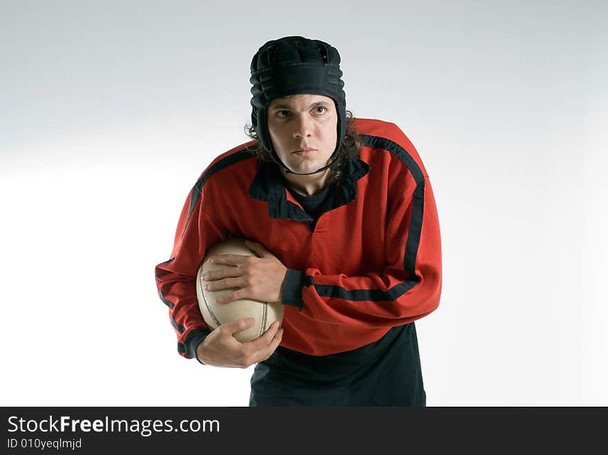 A man, wearing a full rugby uniform, holds the ball tightly, while having a serious look on his face. Horizontally framed shot. A man, wearing a full rugby uniform, holds the ball tightly, while having a serious look on his face. Horizontally framed shot.