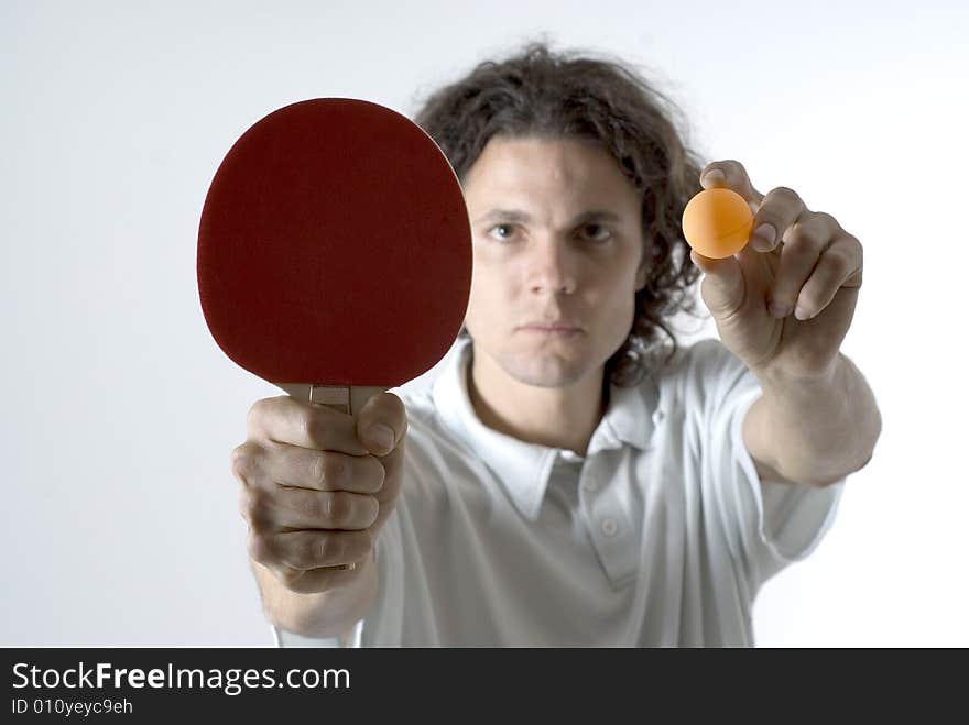 Man holding a table tennis ball and paddle out in front of him with a serious look on his face. Horizontally framed photograph. Man holding a table tennis ball and paddle out in front of him with a serious look on his face. Horizontally framed photograph