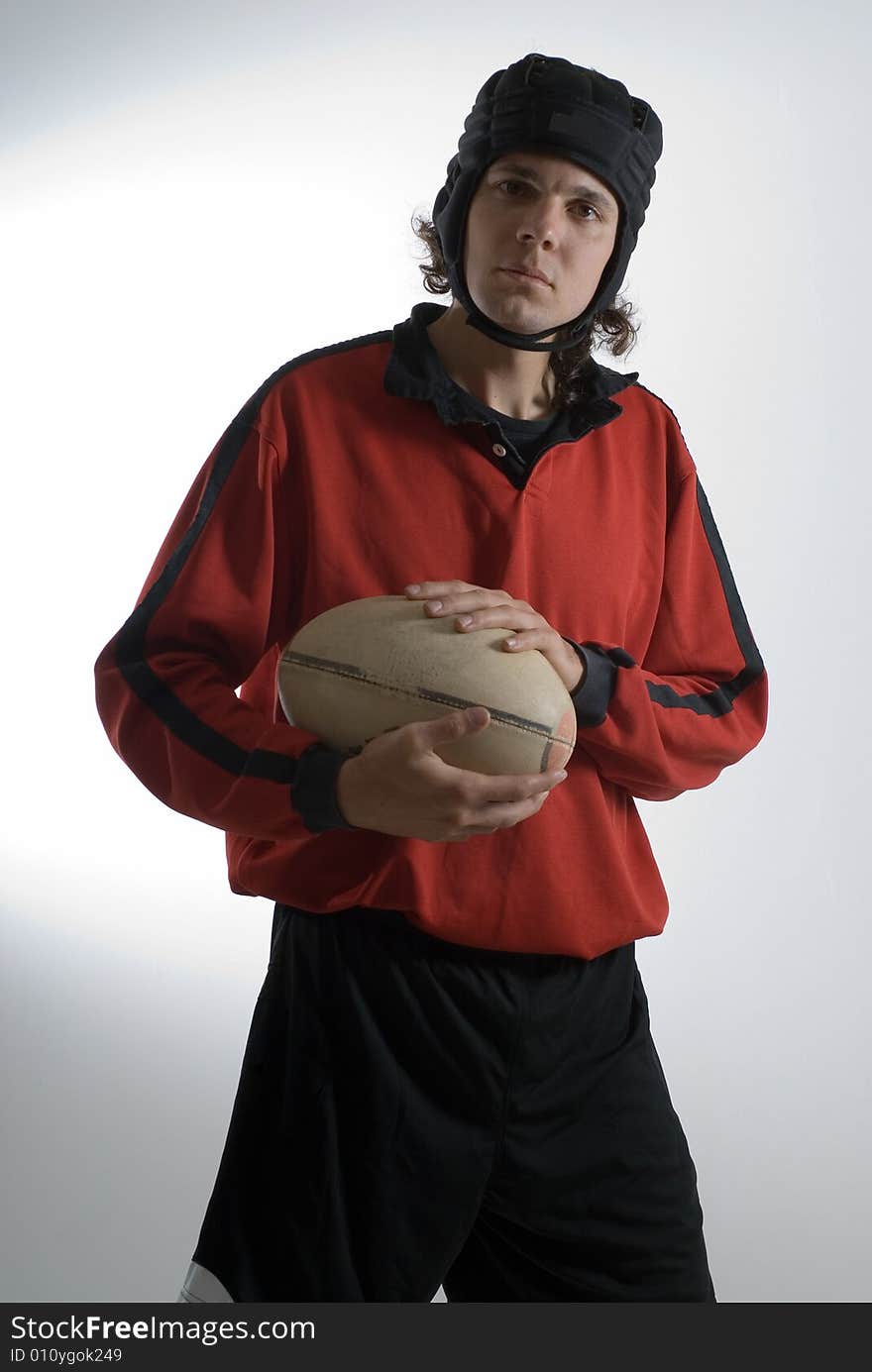 A man, wearing a full rugby outfit, looks serious as he holds the rugby ball. Vertically framed shot. A man, wearing a full rugby outfit, looks serious as he holds the rugby ball. Vertically framed shot.