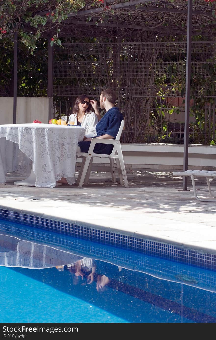 Couple Sitting at Table by Pool - vertical